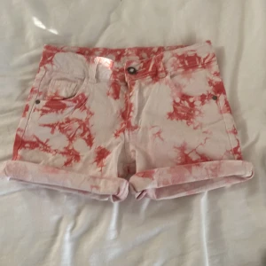 Rosa och vita shorts  - Snygga shorts med coolt batikmönster i rosa och vitt. Klassisk med knapp och dragkedja framtill. Mjukt bomullsmaterial och uppvikta benslut för en chill vibe. Perfekta för varma dagar och sommarhäng.