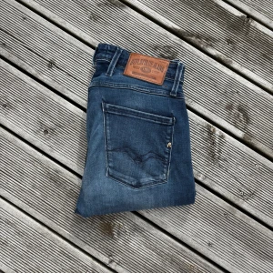 Replay Anbass blå jeans slim fit - ‼️Har någon slags gul avfärgning på högra bakfickan men kan inte ses när dem är på‼️Snygga blå jeans från Replay med klassisk femficksdesign och läderpatch bak i midjan. Jeansen har en slim passform och raka ben, tillverkade i mjukt denimtyg med lätt tvättad look. Perfekta för dig som gillar stilrena och bekväma jeans. Kom gärna med frågor!🙌 W30 L32