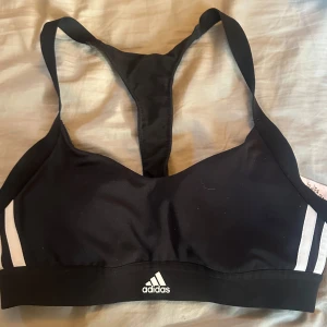Svart sporttopp från Adidas - Sportig svart topp från Adidas med klassiska vita ränder på sidorna och logga framtill. Näsan aldrig använd pga för fel storlek.  Stretchigt material🩷