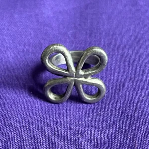 Silverfärgad ring med rosettform - Metallring.  Innerdiameter ca 1,7 mm