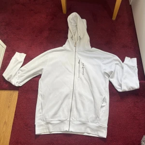 Vit hoodie från Sail Racing med dragkedja - Vit hoodie från Sail Racing i storlek L. Passar i nästans alla outfits använder inte den då den är för stor för mig om Due intresserad är de bara att skicka ett bud så får vi diskutera priset