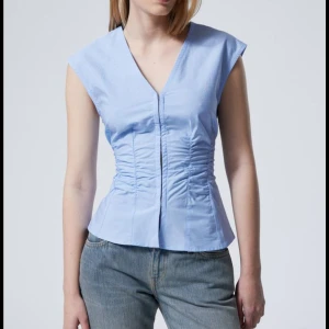 Ljusblå v-ringad topp från Weekday - Säljer en ljusblå ärmlös topp från Weekday med v-ringning och figurnära passform. Lappen är bortklippt då jag tyckte den kliade💞