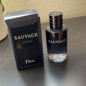 Dior Sauvage Eau de Toilette - Dior Sauvage Eau de Toilette med elegant mörkblå glasflaska och svart lock. Doften är fräsch och maskulin, perfekt för dig som gillar moderna och intensiva parfymer. Snygg originalförpackning medföljer.