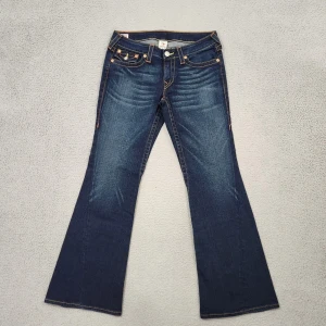 True Religion bootcut jeans  - Snygga blå bootcut jeans från True Religion med  kontrastsömmar. Jeansen har låg midja och har röd tagg bakom vilket betyder att dom är sällsynta och därför värda mer. Använda ett fåtal gånger och i fantastiskt skick, bilder från tidigare ägare. 