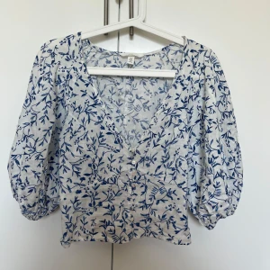 Blommig blus i linneblandning H&M XS - Supersöt blus från H&M i linneblandning, vit med blått blommönster. V-ringad med knappar framtill och puffiga trekvartsärmar. Perfekt för en fräsch och somrig look!