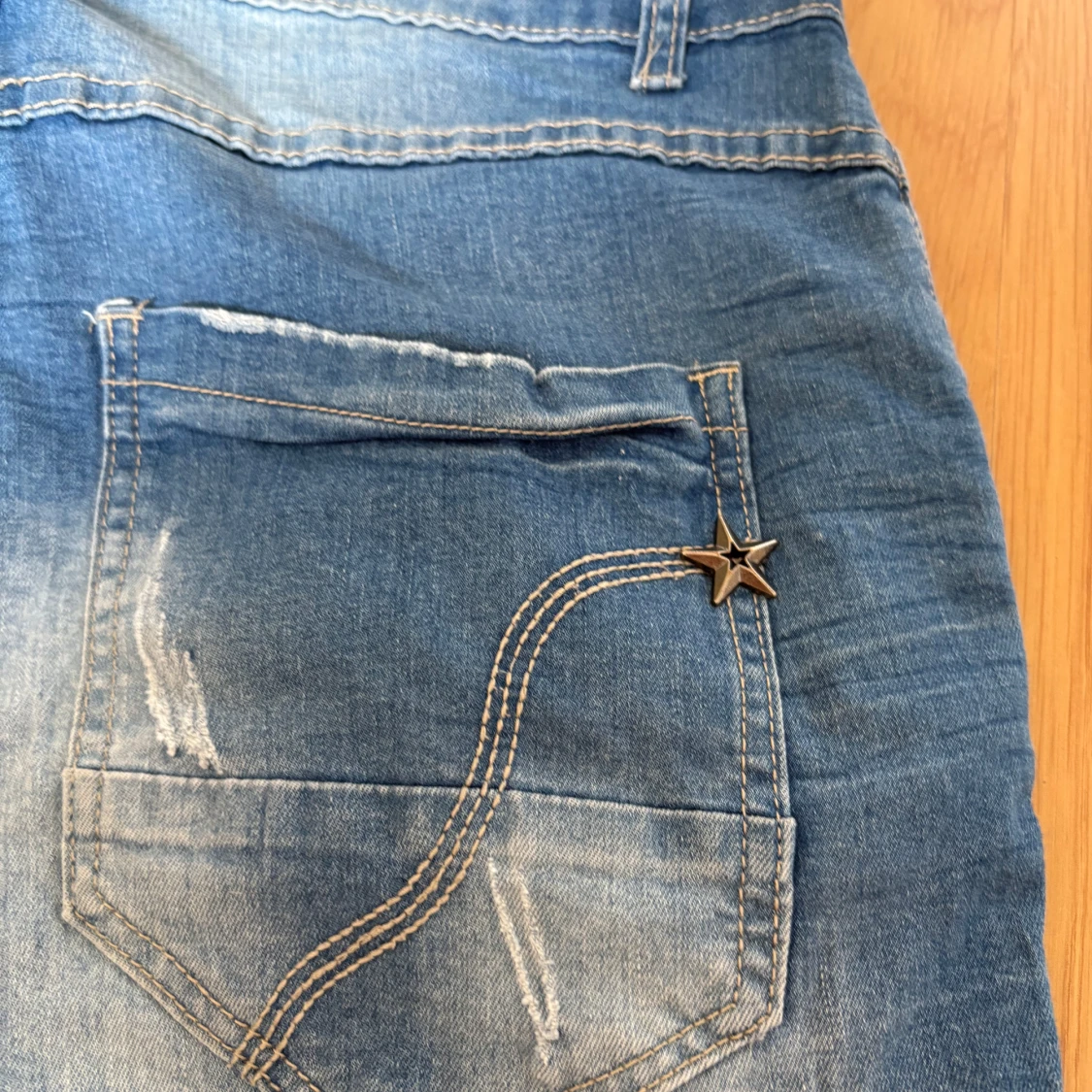 Blå jeans med slitningar och stjärndetalj - 1