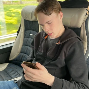 Svart hoodie med dragkedja och orange detalj - Svart hoodie med dragkedja och huva, samt orange detalj vid snörningen. Jackan har långa ärmar och ribbade muddar. Perfekt för dig som gillar en enkel och stilren look med en liten färgklick.