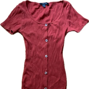 Röd kortklänning  - Röd klänning från Amisu med knappar hela vägen framtill och figurnära passform. Använd några gånger men fortfarande bra skick!