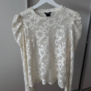 Vit spetsblus med puffärm från Lindex - Superfin vit spetsblus från Lindex i storlek S. Blusen har lång ärm med lätt puff vid axlarna och är helt täckt av ett vackert spetsmönster. Perfekt för dig som gillar romantisk och feminin stil. Rund halsringning och mjukt, tunt material. Använd en gång☺️