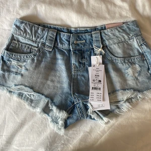 Slutsålda shorts från Gina tricot  - Säljer ett par ljusblåa denim shorts från Gina Tricot i modellen xtra low. De har slitna detaljer, fransig kant och klassisk femficksdesign. Perfekta för varma dagar och ger en cool vibe med sin låga midja. Den är endast testad. Skulle säga att shortsen är ganska stor i storleken och dom passar mer som XS. 