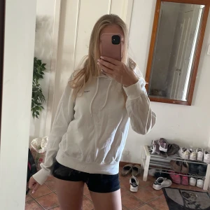 Vit hoodie från Les Amies - Säljer en vit hoodie med en liten svart logga uppe i hörnet. Tröjan har huva med snörning, ribbade muddar och en klassisk passform. Perfekt för chill dagar eller när du vill ha en enkel och clean look. Kan både stylas upp och ner till vardag eller fin middag. Men allra bäst till sommarkvällar!