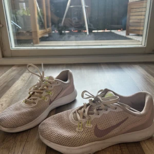 Pink mesh Nike sneakers med rosa swoosh - Lätta och luftiga sneakers från Nike i pink mesh med rosa swoosh på sidorna och detaljer i ljusgult vid snörningen. Skorna har vit sula och klassisk snörning, perfekt för dig som gillar sportig och clean stil.