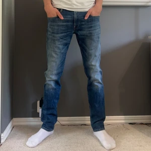 Replay Anbass slim fit - Snygga blå Replay Anbass jeans i slim fit med klassisk femficksdesign och diskreta slitningar. Jeansen har medelhög midja och raka ben. Storlek W32 och L32.