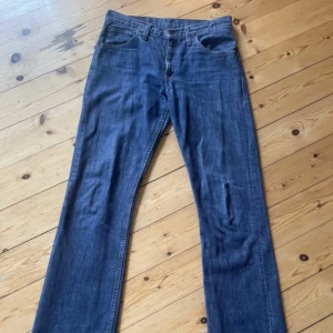 Levi's 507 raka jeans med rå kant - Säljer ett par klassiska Levi's 507 jeans i mörkblå denim. Jeansen har raka ben och rå, fransad kant nertill 