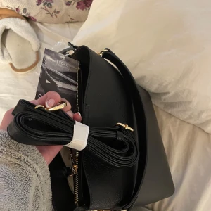 Svart axelväska från Lycke Oslo - En mycket fin svart väska med gulddetaljer! Den är helt ny och har prislappen kvar. Väskan har flera fack och har bra med utrymme. Det finns både ett kortare och ett längre band! Nypris 699💗