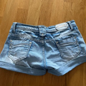 Ljusblå jeansshorts - Snygga ljusblå jeansshorts från Miss Sixty med klassisk femficksmodell, uppvikta benslut och coola detaljer på bakfickorna. kontakta för midjemått🥰 säljer då dem är för små för mig.