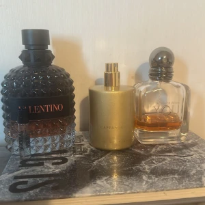 Parfympaket: Valentino, Armani, Scandal - Säljer ett parfympaket med tre flaskor: Valentino Uomo i mörk, mönstrad glasflaska med svart kork, Giorgio Armani Stronger With You i genomskinlig fyrkantig flaska med silverkork, samt en liten provflaska Scandal från Jean Paul Gaultier. Snygga flaskor och ikoniska dofter, skicka  meddelande om du vill köpa en av dem.                           Valentino -60 till 65 ml, stronger with you intensly -15 ml, cappadocia royal platinum - 48 ml, provdoft jean Paul scandal -1,5 ml