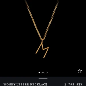 Guldigt halsband med bokstav M - Snyggt halsband i guld med en unik, sned bokstav E som hänge. Kedjan är klassisk och stilren, perfekt för dig som vill ha ett personligt smycke med cool twist. Passar lika bra till vardags som till att lyfta din outfit.