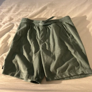 Gröna frottéshorts från Warp - Mysiga gröna shorts från Warp i mjuk frotté med elastisk midja och snörning. Perfekta för chill dagar eller när du vill ha något bekvämt på sommaren. Enkel design utan mönster och med avslappnad passform.