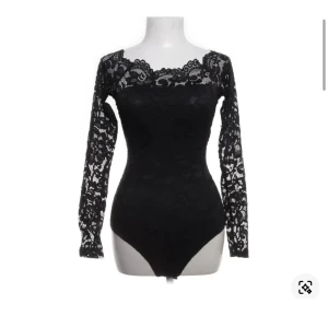 Spetsbody - Säljer en svart body med långärmade ärmar och offshoulder-modell. Bodyn har blommigt spetsmönster och en snygg, figurnära passform. 