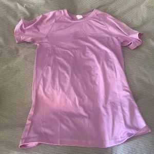 Ljuslila/ljusrosa tight träningströja  - En enkel och stilren ljuslila/ljusrosa träningst-shirt med rund halsringning och korta ärmar. T-shirten har en rak passform och är tillverkad i ett mjukt material som känns skönt mot huden. 