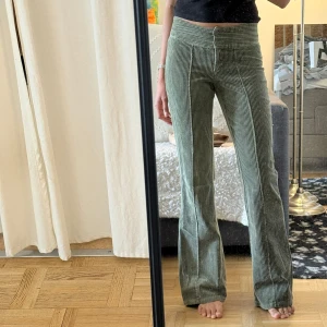 Gröna manchesterbyxor med bootcut - Snygga gröna manchesterbyxor med breda ben och bootcut-silhuett. Byxorna har hög midja och klassiska lodräta ränder i tyget. Perfekta för dig som gillar retrovibbar och vill ha ett par bekväma men trendiga byxor.