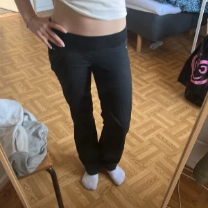 Svarta bootcut byxor med stretchmidja - Säljer ett par svarta byxor med bootcut-snitt och bred, stretchig midja. Byxorna har fickor fram och bak samt en mjuk känsla i materialet. Perfekta för dig som gillar en bekväm och stilren look.
