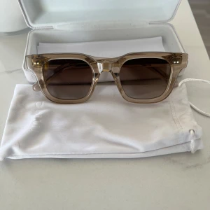  Chimi 04 ecru  - Snygga solglasögon från Chimi med transparent beige båge och fyrkantig form. Glasen är bruna och ger en cool retrovibe. Perfekta för dig som vill sticka ut med stilrena accessoarer. Kommer med originalfodral och påse. Använda 2 gånger 10/10 skick. Inte kvar kvitto för att köpet var gjort för längesedan. 