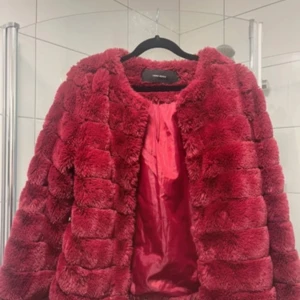 Röd pälsjacka från Vero Moda - Säljer en fluffig och snygg röd pälsjacka från Vero Moda i storlek S. Jackan är gjord i fuskpäls! Perfekt för dig som vill sticka ut och hålla dig varm under kyliga dagar. Den är knappt använd så skicket är otroligt bra.