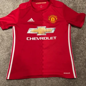 Manchester United Ibrahimović tröja - Röd Manchester United matchtröja från Adidas med Zlatan Ibrahimović och nummer 9 på ryggen. Tröjan har klubbmärke på bröstet, Chevrolet-logga och vita detaljer längs sidorna. Tillverkad i lätt och ventilerande climacool-material. Tröjan är äkta. Skick-8/10 väldigt bra det enda är att numret är skrynkligt. Det är en storlek L för barn