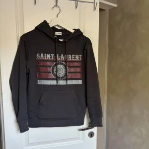 Grå Saint Laurent Hoodie   - Tjena, säljer nu denna riktigt feta Saint Laurent hoodien i storlek (S) passar (XS). Extremt schysst nu till sommaren, hör av er vid fler frågor eller funderingar!