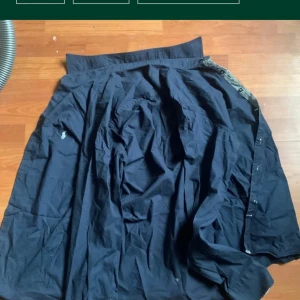 Mörkblå skjorta från Ralph Lauren - Klassisk mörkblå skjorta från Ralph Lauren med broderad logga på bröstet. Skjortan har knappar framtill och är tillverkad i bomull. Perfekt för en stilren och avslappnad look.