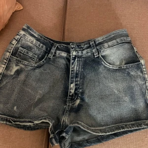 Blåa jeansshorts med vingar - Snygga blåa jeansshorts med slitna detaljer och coola broderade vingar i silver på bakfickorna. Tyvärr för stora för mig därav säljer, aldrig använda. Dem är lite stora i storleken så skulle säga att dem hade passat någon som hade S/34 eller 38. Skriv gärna för mått!! 
