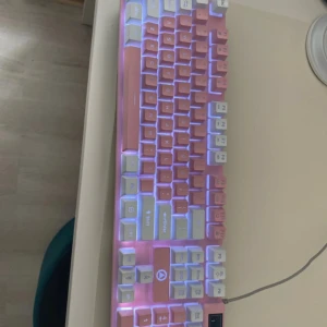 Tangentbord  - rosa och vitt tangentbord med bakgrundsbelysning och USB-anslutning. Tangentbordet har en modern och färgglad design. SL knappen sätter på och av ljuset
