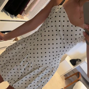 Vit prickig kort klänning - Supersöt vit kort klänning med svarta prickar och smala axelband. Klänningen har även än dragkedja på sidan! Aldrig använd!