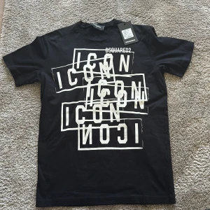 Svart Dsquared2 Icon t-shirt M - Svart t-shirt från Dsquared2 i storlek M med coolt vitt 'ICON'-tryck i flera lager på framsidan. Klassisk rund hals och korta ärmar. Tillverkad i mjuk bomull som känns skön mot huden. Perfekt för dig som vill sticka ut med en statement-tee. Pris går att diskuteras då jag fick den som en present från min pappas kompis som jobbar på Dsquared2. Den är helt ny aldrig använd men vill bara bli av med den är inte min stil