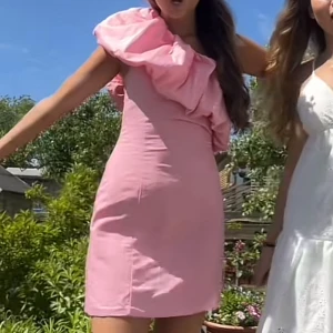 Rosa kort klänning med volang - !Oanvänd, med lappar! Superfin rosa kortklänning med en stor volangdetalj över ena axeln och är figursydd💕 slutsåld! Nypris 450kr