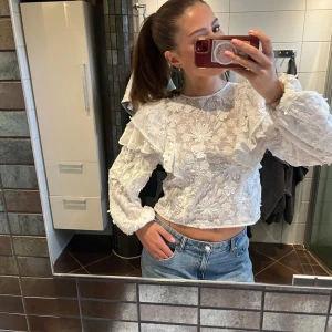 Vit blus från & other stories  - Superfin vit blus med broderade blommor och volangdetaljer på axlarna. Blusen, har långa puffärmar och är genombruten med spetskänsla. Inte genomskinlig alls och sitter så fint! Nypris 1800 kr
