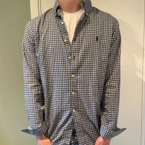 Rutig skjorta från Ralph Lauren - Snygg rutig skjorta från Ralph Lauren i blått och vitt. Klassisk krage, knäppning framtill och lång ärm. Skjortan är i bomull och har en normal passform. Perfekt för dig som gillar stilrena och tidlösa plagg.