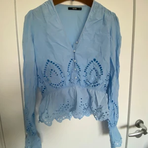 Ljus blå blus - En jättefin ljusblå blus, perfekt nu till sommaren! Otroligt fina detaljer på den så som en resor i midjan och längst ner i ärmarna vilket gör volanger längst ner! Jag säljer för att den har blivit för lite .