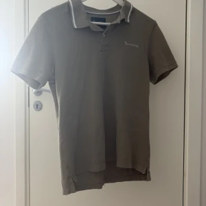 Grön  pikétröja från Bondelid strl S - Säljer en stilren beige pikétröja från Bondelid med klassisk krage och diskret logga på bröstet. Tröjan har korta ärmar och vit rand på kragen för en sportig touch. Perfekt för dig som gillar en clean och tidlös look. Skick 8,5/10, storlek är S men passar även XS