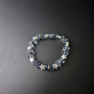 Armband med blå pärlor och stjärnor - Snyggt armband med facetterade blå pärlor, vita stjärnformade pärlor och glittriga silvriga mellanringar. 
