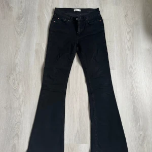 Svarta bootcut jeans från Perfect Jeans - Svarta jeans från Perfect Jeans med bootcut-modell och hög midja. Klassisk femficksdesign, kopparfärgade nitar och dragkedja. Jeansen är i stretchigt denimtyg som sitter snyggt över höfterna och släpper ut vid benen.