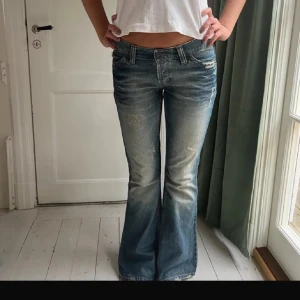 River Island Jeans - Supersnygga Jeans från river Island i lågmidjad bootcutmodell. De sitter precis som på första bilden men har valt att klippa hål i de (se bild 3). Midjemåttet är 40cm och innerbenslängden är 80cm. De har en litet slitning på varje benslut bak, därav priset 💗