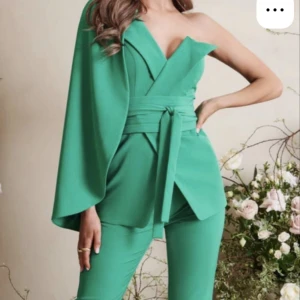 Grön set Lavish Alice - Säljer en grön kostym set med unik asymmetrisk design och enaxlad kavaj från Lavish Alice. Kavajen har ett brett bälte i midjan och vida ärmar på ena sidan. Byxorna är smala och ankellånga. Priset kan diskuteras🤍