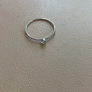 Silverring med liten sten - Elegant och enkel silverring med en liten klar sten. Perfekt för en minimalistisk stil eller som en del av en ringstack. Ringen har en tunn banddesign som ger en subtil och stilren look.