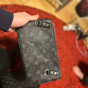 Svart axelväska med monogram - Snygg svart axelväska med monogrammönster och dragkedja. Perfekt för att bära dina nödvändigheter med stil. Väskan har eleganta detaljer och en praktisk storlek.