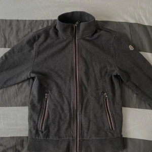 Moncler Maglia Cardigan  - En snygg, stilren och bekvämlig Moncler Maglia Cardigan. Materialet är tungt vilket gör tröjan varm. En perfekt unik vår tröja. Den är i väldigt bra skick, i princip ny. Storlek L men passar mer M. Priset går att diskutera vid snabb affär!
