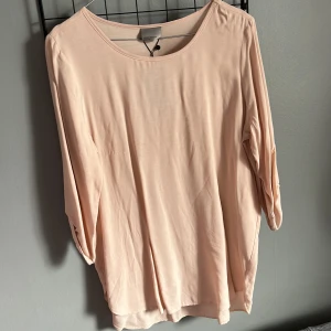 Beige topp från Vero Moda - Säljer en stilren beige topp från Vero Moda. Toppen har trekvartsärmar med knappdetalj och en rund halsringning. 