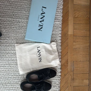 Lanvins svarta  - Kan mötas upp i Stockholm regionen. Sen är pris diskuterbart vid snabb affär. Snygga svarta sneakers från Lanvin med snörning och rund tå. Skorna har en stilren design med en kombination av skinn och syntetmaterial. Perfekta för en trendig look. Storlek 41,42,43 helt perfekta om du vill ragga upp någon tjej. De är använda 10-11 gånger. Köpta för 5200kr från NK. 
